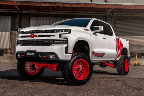 White lifted Chevrolet Silverado with red wheels.