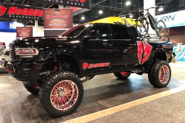 Black pickup truck with red rims and a bike rack.