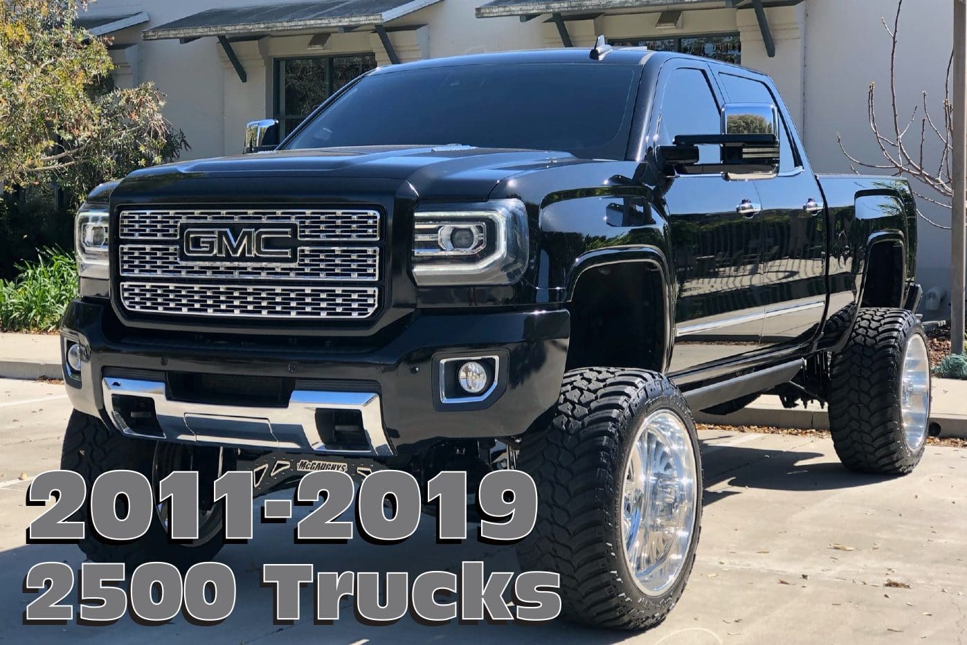 Black GMC 2500 pickup truck with large wheels.