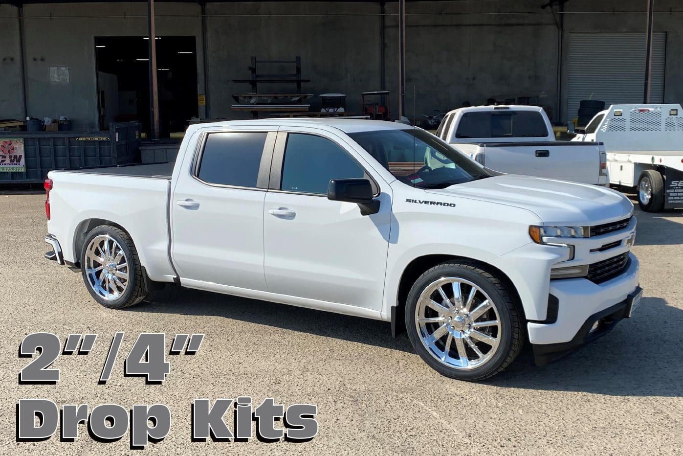 White Chevrolet Silverado truck with drop kits.