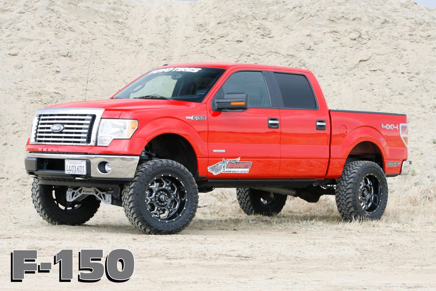 Red Ford F-150 pickup truck on dirt.