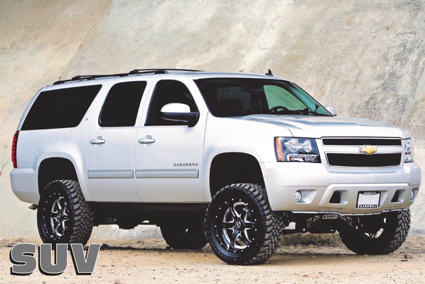 White Chevrolet Suburban SUV parked on dirt.