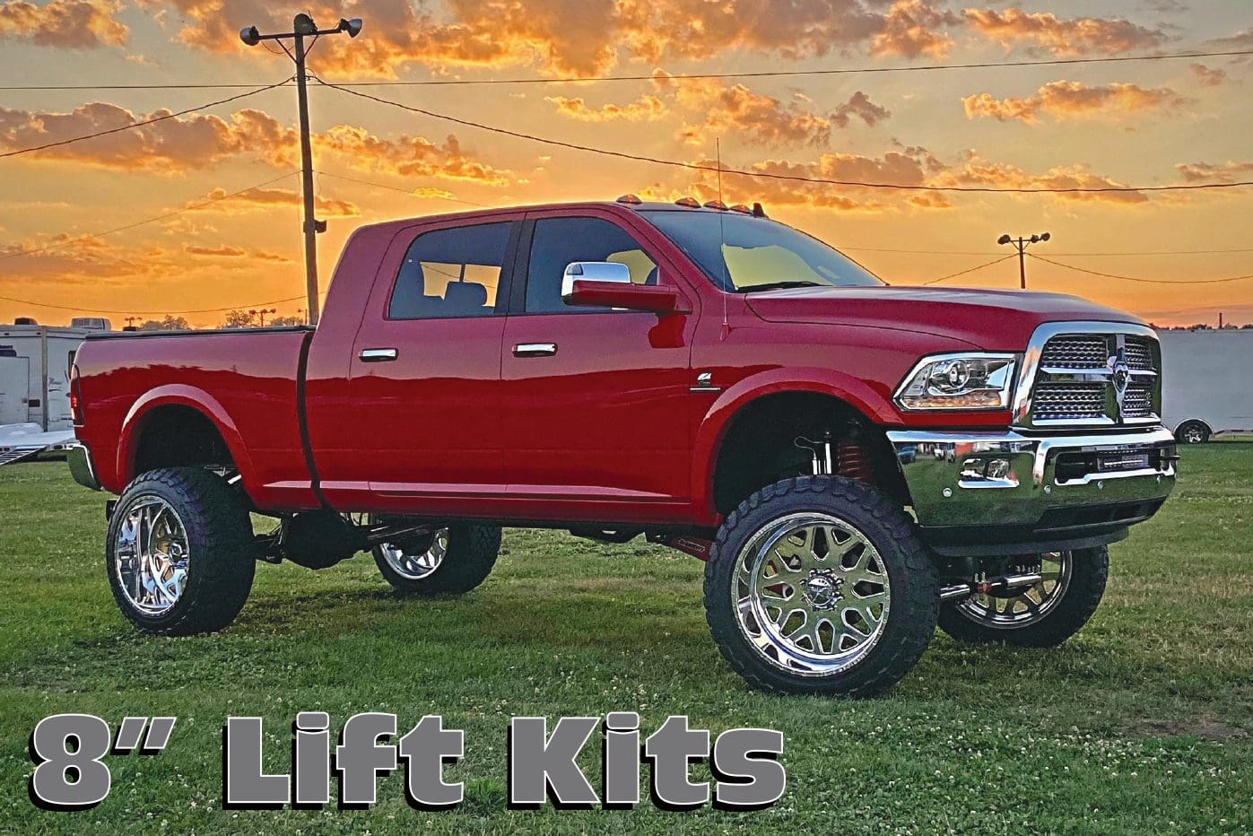 A red truck with huge tires is parked in the grass.