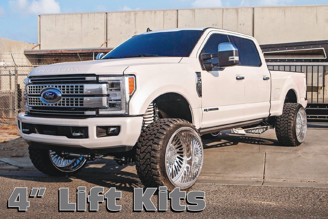 A white truck with large tires on the side of it.