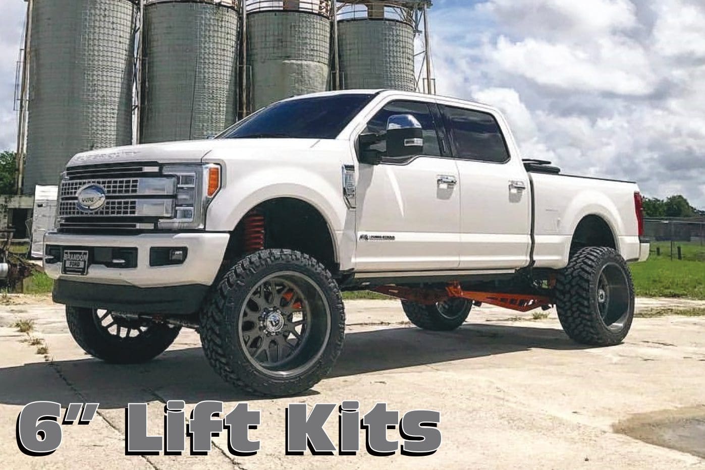 A white truck with large tires and big wheels.